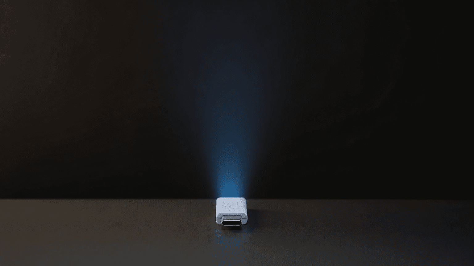 A single white USB-C drive on a dark surface with a faint Tesla-blue light beam emerging from it: Tesla lock sound install