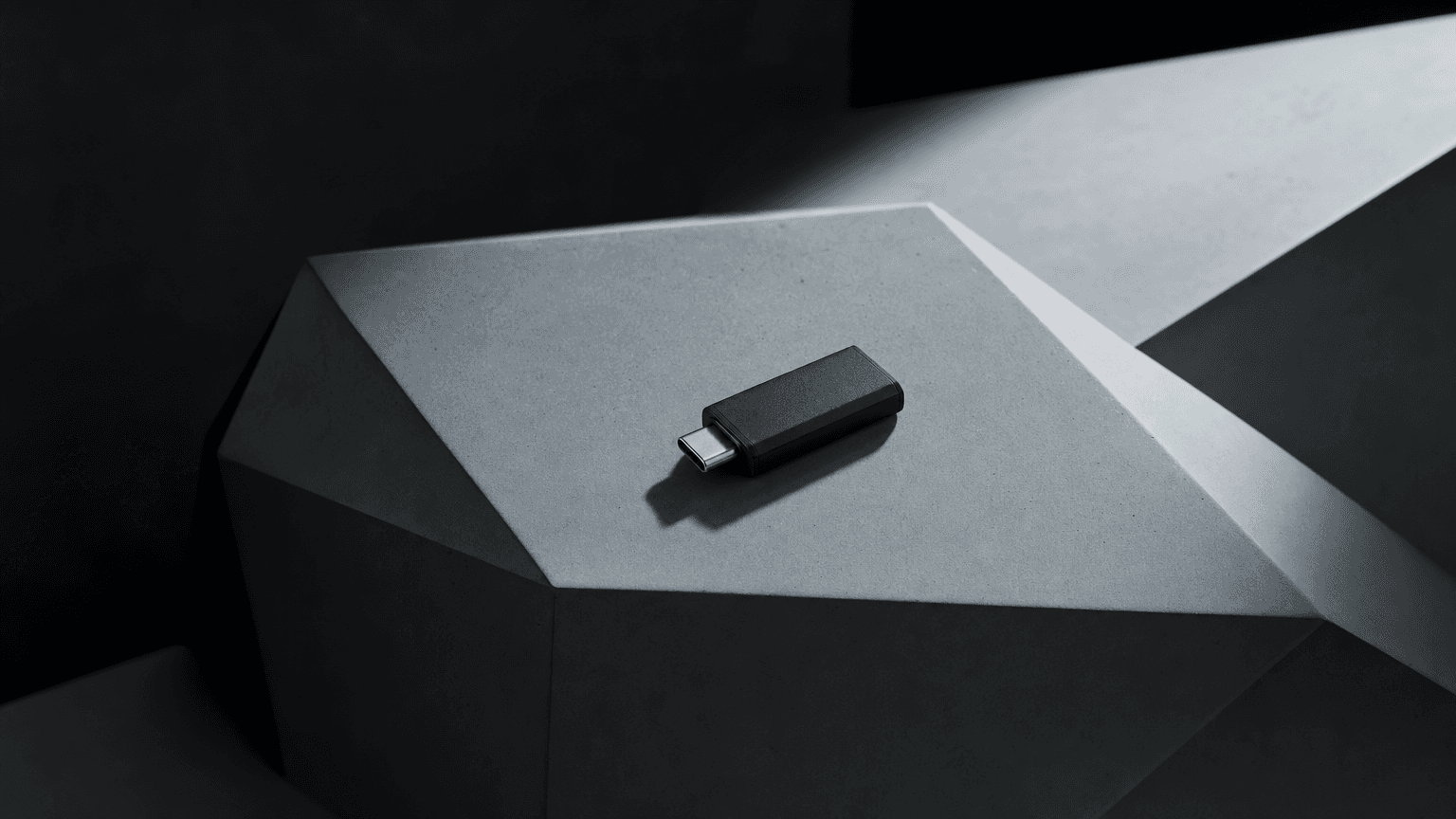 USB-C cable entering a port on a faceted angular grey surface evoking Cybertruck geometry