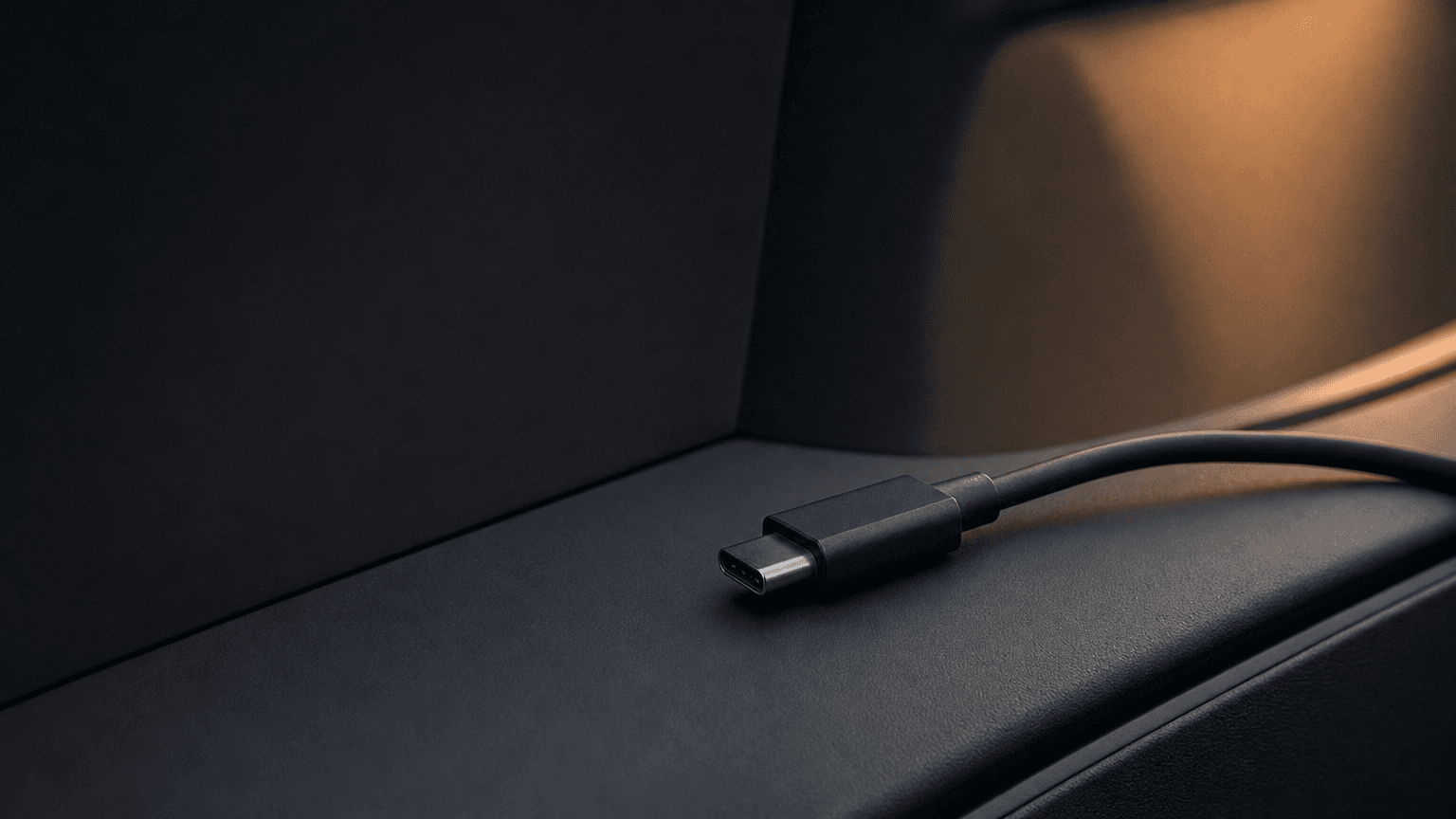 USB-C cable inserted into a Tesla Model 3 dashboard USB-C port with warm interior light spill